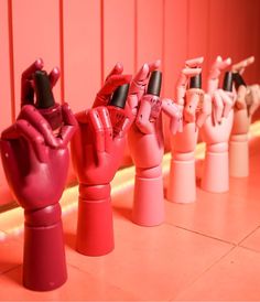 a row of pink and red hand - shaped objects in front of an orange wall