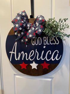 a patriotic door hanger with the words god bless america painted on it and a potted plant