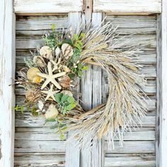 a wreath is hanging on an old door with seashells and starfish in it