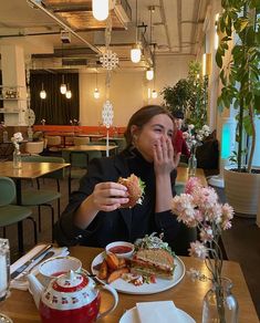 a woman sitting at a table with food in front of her and flowers on the table