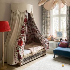 a canopy bed in the corner of a room with curtains on the windowsills