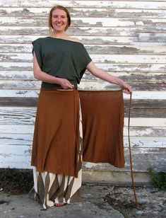 a woman standing in front of a white building with a brown skirt and green top