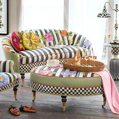 a living room with checkered furniture and colorful pillows on the couches, rugs and footstools