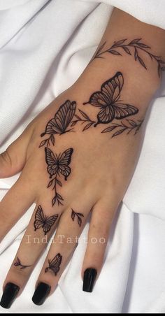 a woman's hand with tattoos on it and butterflies flying around the wrist,