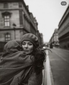 black and white photograph of a woman wrapped in a blanket on the side of a street