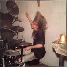 a man with long hair playing drums in a room