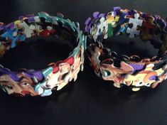 two bracelets made out of puzzle pieces on a black surface with one missing the clasp