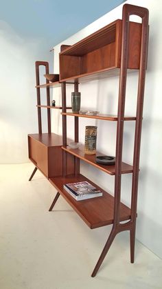 a wooden shelf with books and magazines on it in a white walled room next to a wall