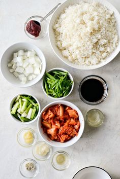 bowls filled with food sitting on top of a table next to glasses and sauces