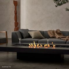 a living room with a couch, table and fire pit in front of the wall