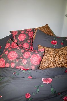 an unmade bed with pink flowers and leopard print pillows