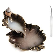 an egg is sitting on top of a leaf shaped dish next to a pair of scissors