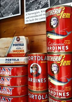 several tins of sardines are stacked on top of each other in front of pictures