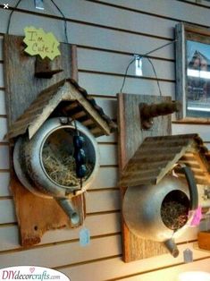 two bird houses hanging on the side of a wall with birds in it's feeders