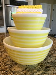 three large yellow bowls stacked on top of each other in front of a microwave oven