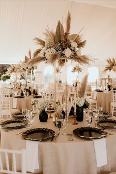 the table is set with black and white plates, silverware, and tall centerpieces