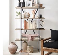 a book shelf filled with lots of books and vases next to a chair in a room