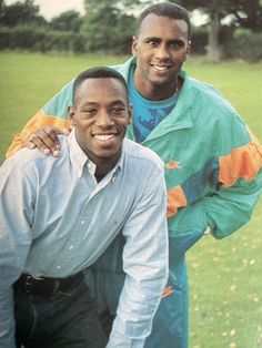 two men standing next to each other in a field