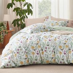 the comforter is made up with flowers and leaves on it, along with two pillows