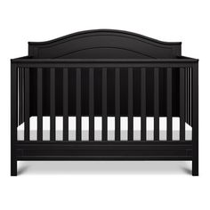 a black crib with white sheets on it