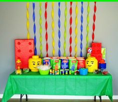 a green table topped with lots of legos and candy bar decorations on top of it