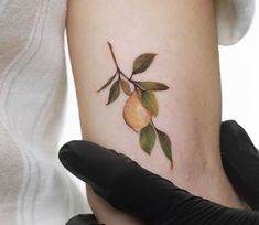 a woman with a tattoo on her arm holding a glove and an apple tree branch