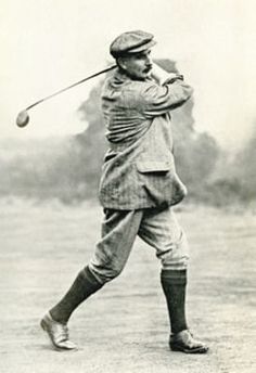 an old black and white photo of a man swinging a golf club at a ball