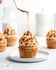 a cupcake being drizzled with caramel icing on a white plate