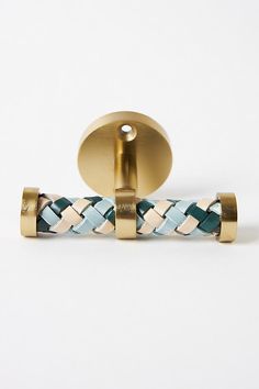 a pair of gold and blue braided cufflinks on a white background,