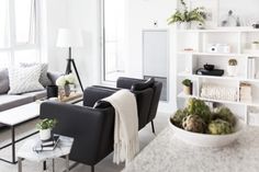 a living room filled with furniture and a white table topped with a bowl of plants