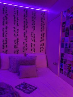 a bed with purple lights and pillows on top of it in front of a wall