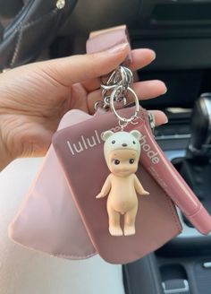 a person holding a keychain with a small animal on it's side