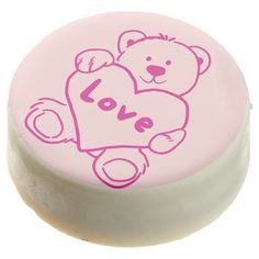 a pink and white round box with a teddy bear on it's back that says love