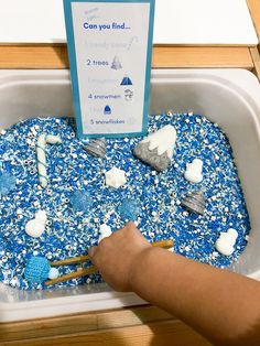 a child's hand is playing with blue and white sprinkles