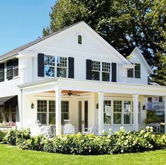 a large white house with black shutters on the front and side windows is shown