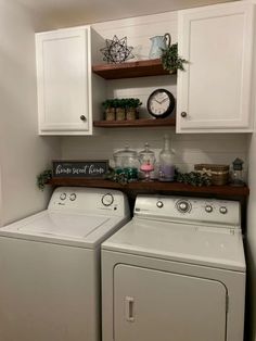 a white washer and dryer sitting in a kitchen next to cabinets with shelves above them