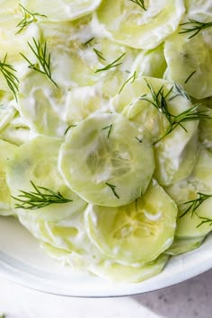 cucumber salad with dill and sour cream in a white bowl on a table