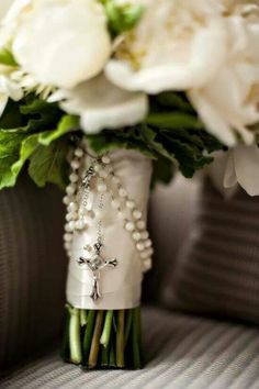 a bridal bouquet with white flowers and pearls is sitting in a vase on a couch