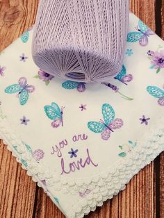 a purple ball of yarn sitting on top of a doily next to a piece of cloth