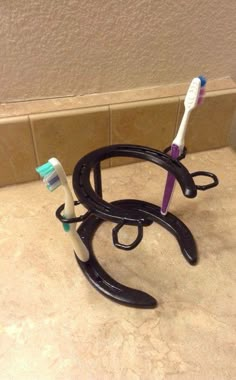 two toothbrush holders sitting on top of a counter next to a tiled wall and floor