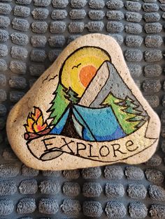 a rock with the words explore painted on it and an image of a campfire