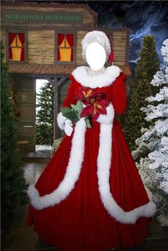 a woman dressed as santa claus standing in front of a christmas tree