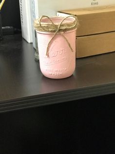 a pink mason jar sitting on top of a black table next to a stack of books