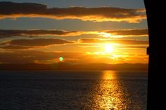 the sun is setting over the ocean with clouds in the sky and water below it