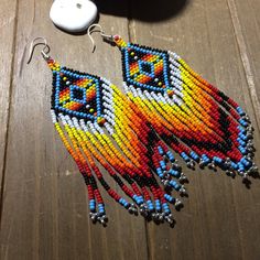 a pair of colorful beaded earrings sitting on top of a wooden table next to a computer mouse