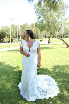 a woman standing in the grass wearing a white dress