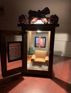 a small wooden box with a chair inside and a christmas tree in the corner behind it