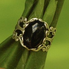 14 x 10mm black onyx cabochon on an antiqued sterling silver plated adjustable filigree ring. Easy to adjust to any size.Black onyx has traditionally been used to banish grief and enhance self-control. Modern Goth, Black Onyx Stone, Vintage Style Jewellery, White Howlite, Snowflake Obsidian, Halloween Jewelry, Filigree Ring, Onyx Stone, Black Rings