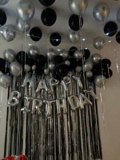 balloons and streamers are hanging from the ceiling in front of a happy birthday sign