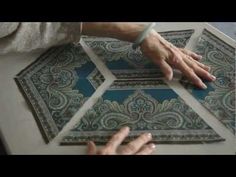 two people are working on an intricately designed piece of art that is being held by their hands